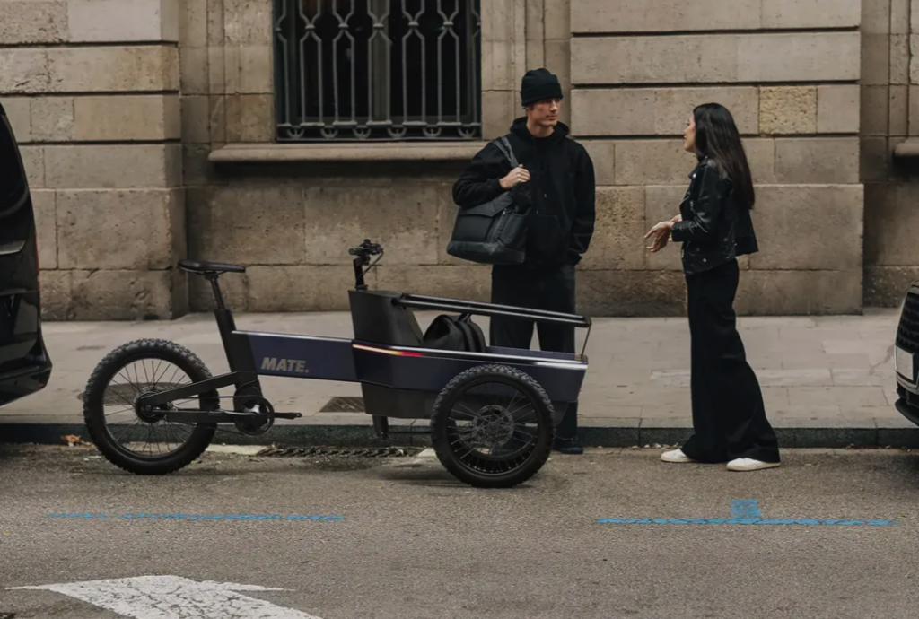 MATE SUV Cargobike Der MATE SUV wurde als perfekte Alternative zum Auto entwickelt, mit der Sie sich problemlos durch die Stadt bewegen und den Verkehr umgehen können. Ob Sie mit Ihren Kindern auf dem täglichen Schulweg, Ihrem Partner oder einem Freund unterwegs sind, auf den MATE SUV können Sie sich im Alltag verlassen. Mit einer Akkuladung legt der MATE SUV bis zu 100 km zurück und bewältigt auch schwere Lasten mit Leichtigkeit. Der starke Mittelmotor mit Tretunterstützung ermöglicht ein müheloses und bequemes Manövrieren. Mit der optionalen Regenschutzhaube müssen Sie auch an Regentagen nicht nach dem Autoschlüssel greifen und können Ihre Waren sicher ausliefern. Der MATE SUV mit seinem modularen Design und einer Reihe von Optionen bietet Ihnen die Freiheit, jede Version von Ihnen zu entdecken. Eine Auswahl an Kasteninterieur, das Allwetterdach, die Geländereifen und die exklusive MATE Wing-Technologie machen ihn zum vielseitigsten SUV auf dem Markt.